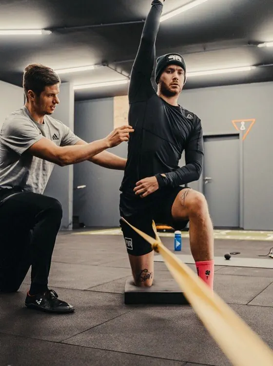 Deportista en rehabilitación con carga progresiva junto a su kinesiólogo